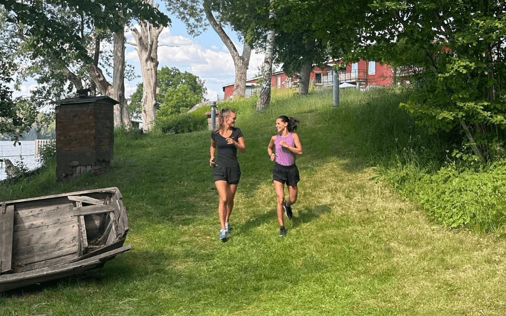 Två kvinnor joggar och pratar med varandra.