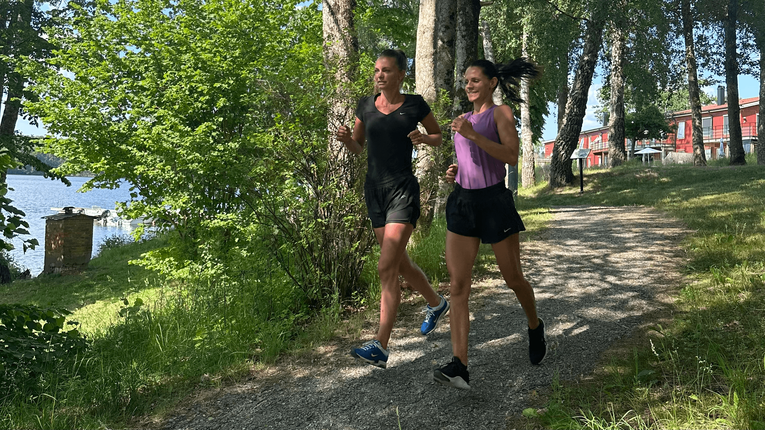 Två kvinnor joggar på en promenadstig.