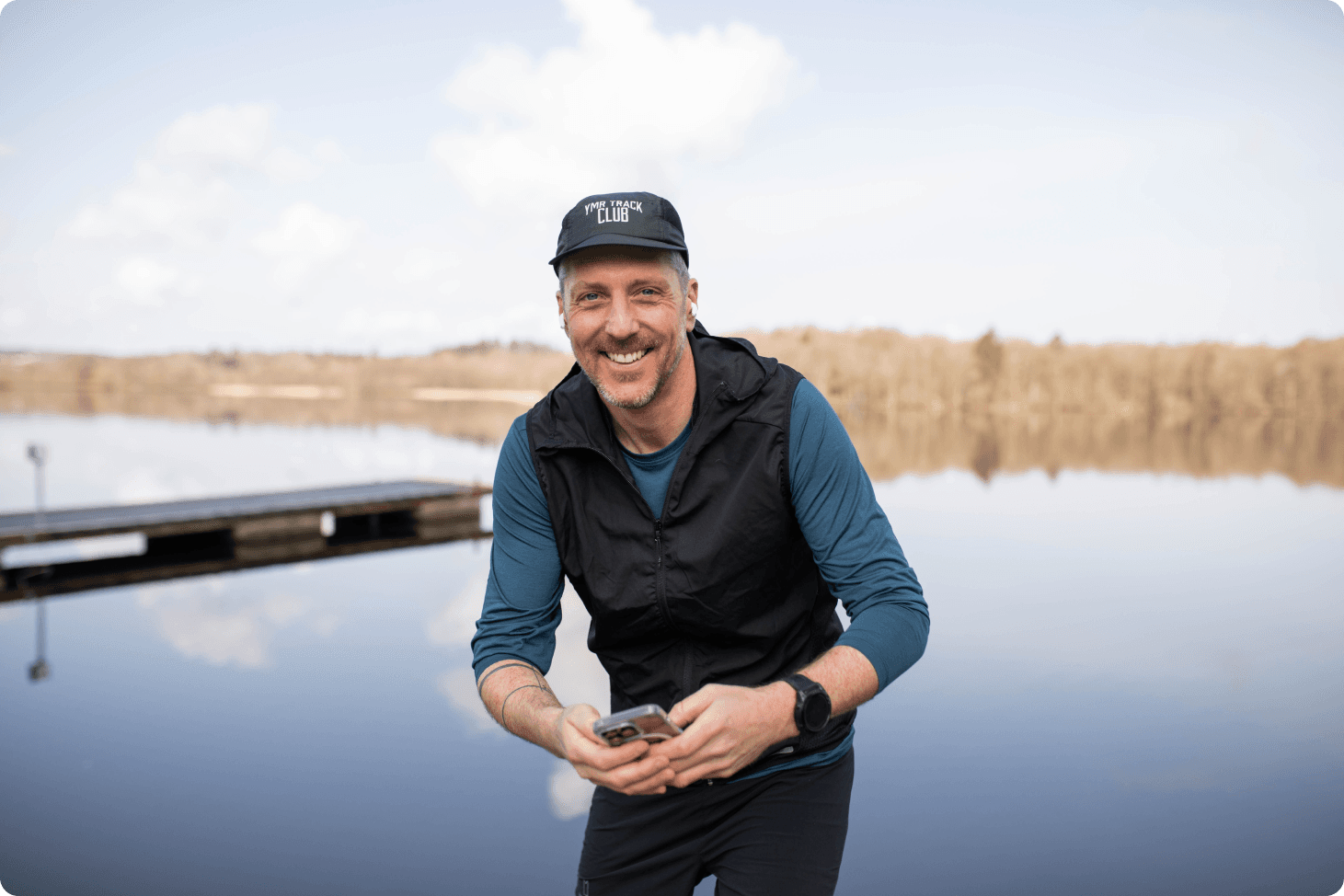 Löpcoach Micke står vid vattnet och håller sin mobil i handen.