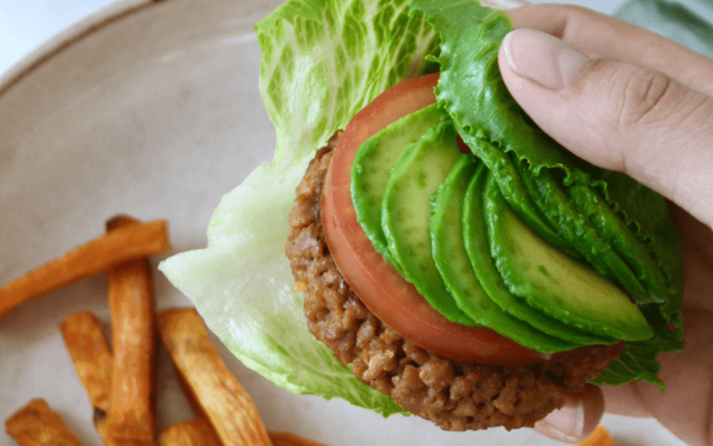Nyttig hamburgare med salladsblad, avokado och tomat.