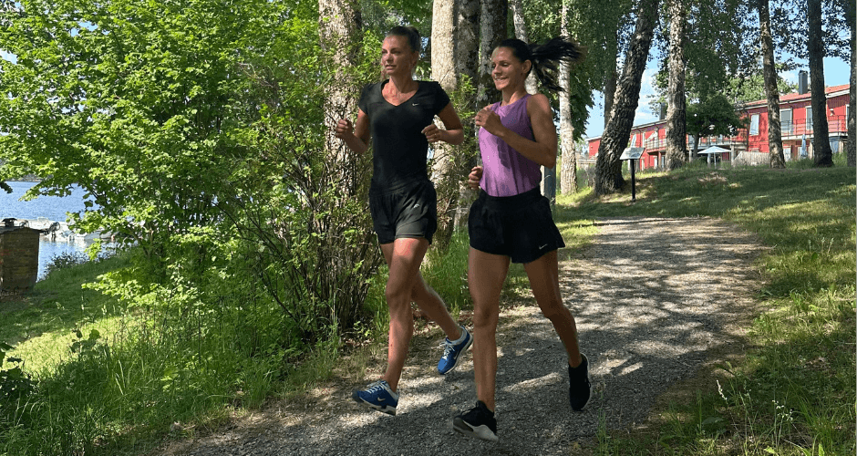 Två kvinnor jobbar ner för en backe på en promenadväg.