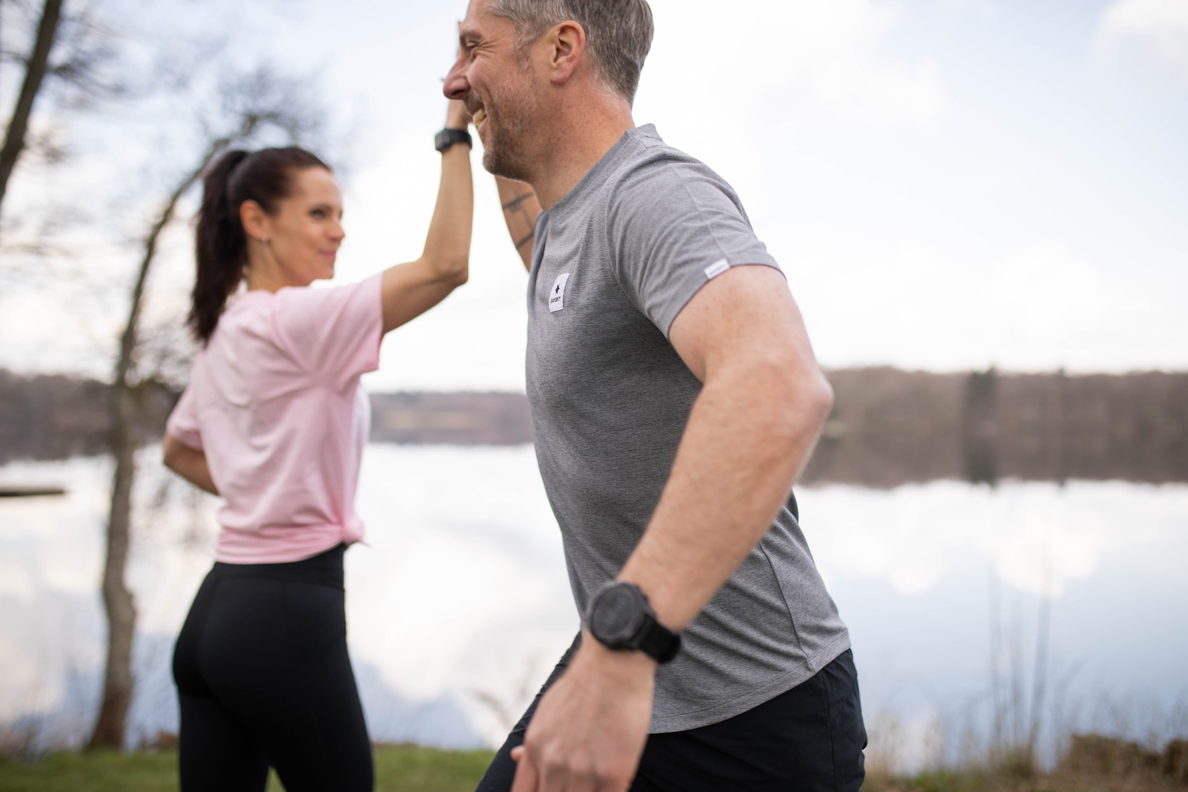 Man och kvinna är vid vattnet och gör high five med varandra.