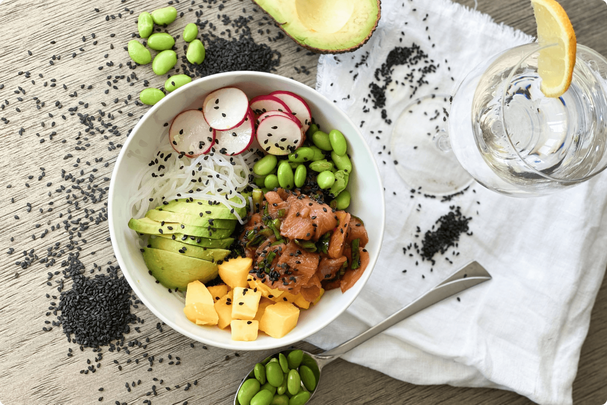 Hemmgjord pokébowl med lax, avokado, rädisor, gröna bönor, mango och nudlar.