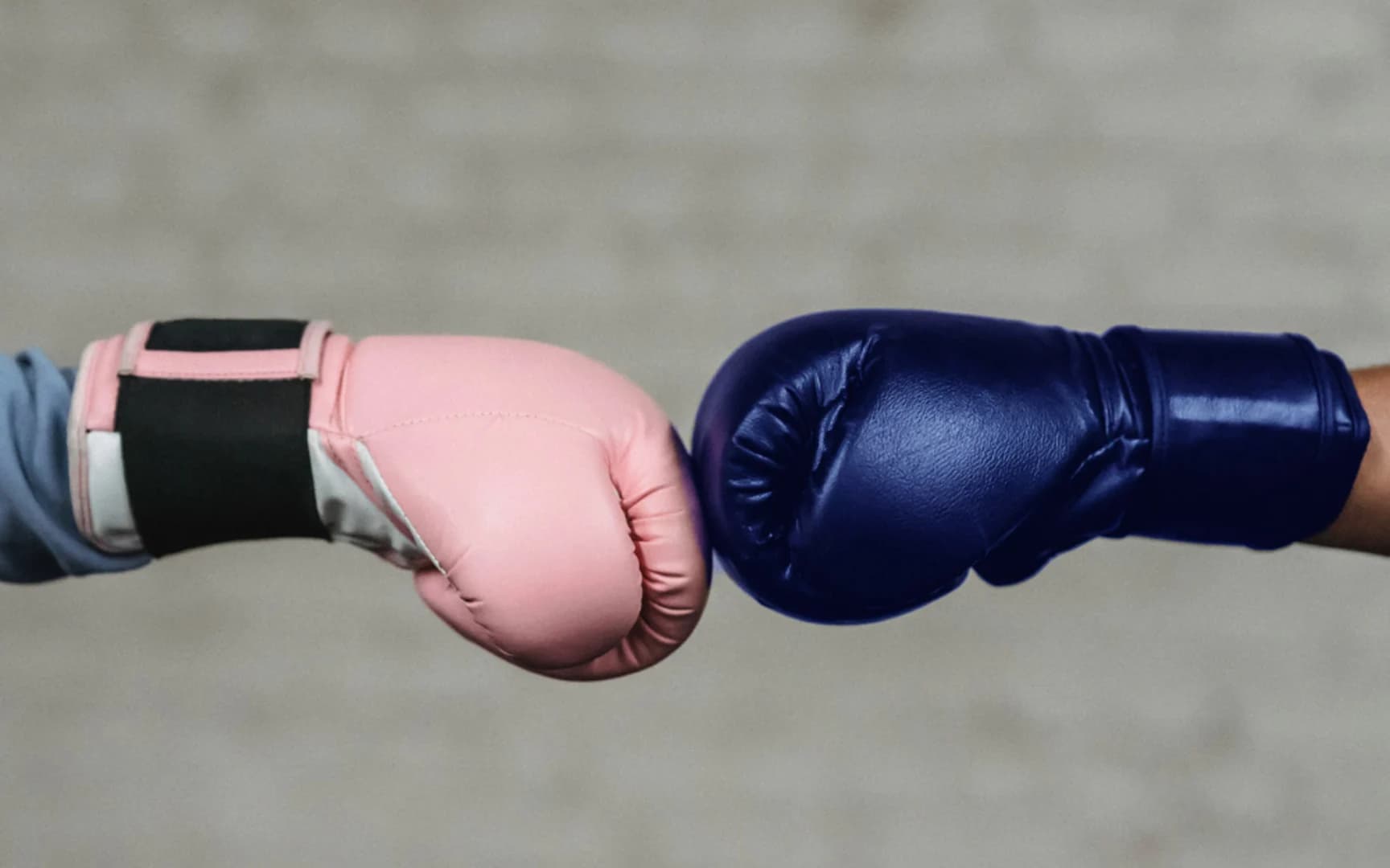 En rosa boxningshandske slår mot en blå boxningshandske