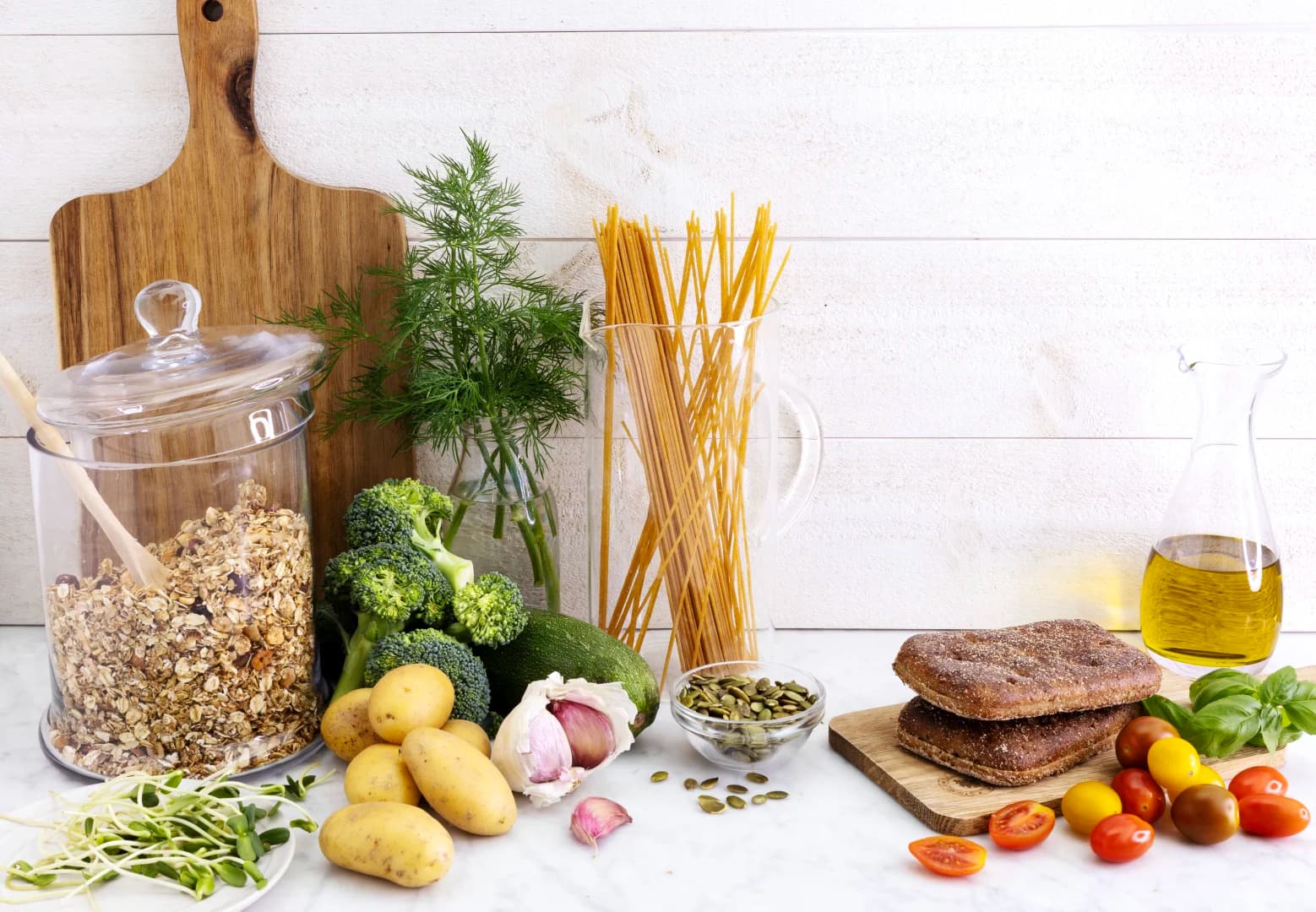 Bild som visar olika nyttiga råvaror som pasta, potatis, broccolo, grovt bröd, minitomater, olivolja, granola.