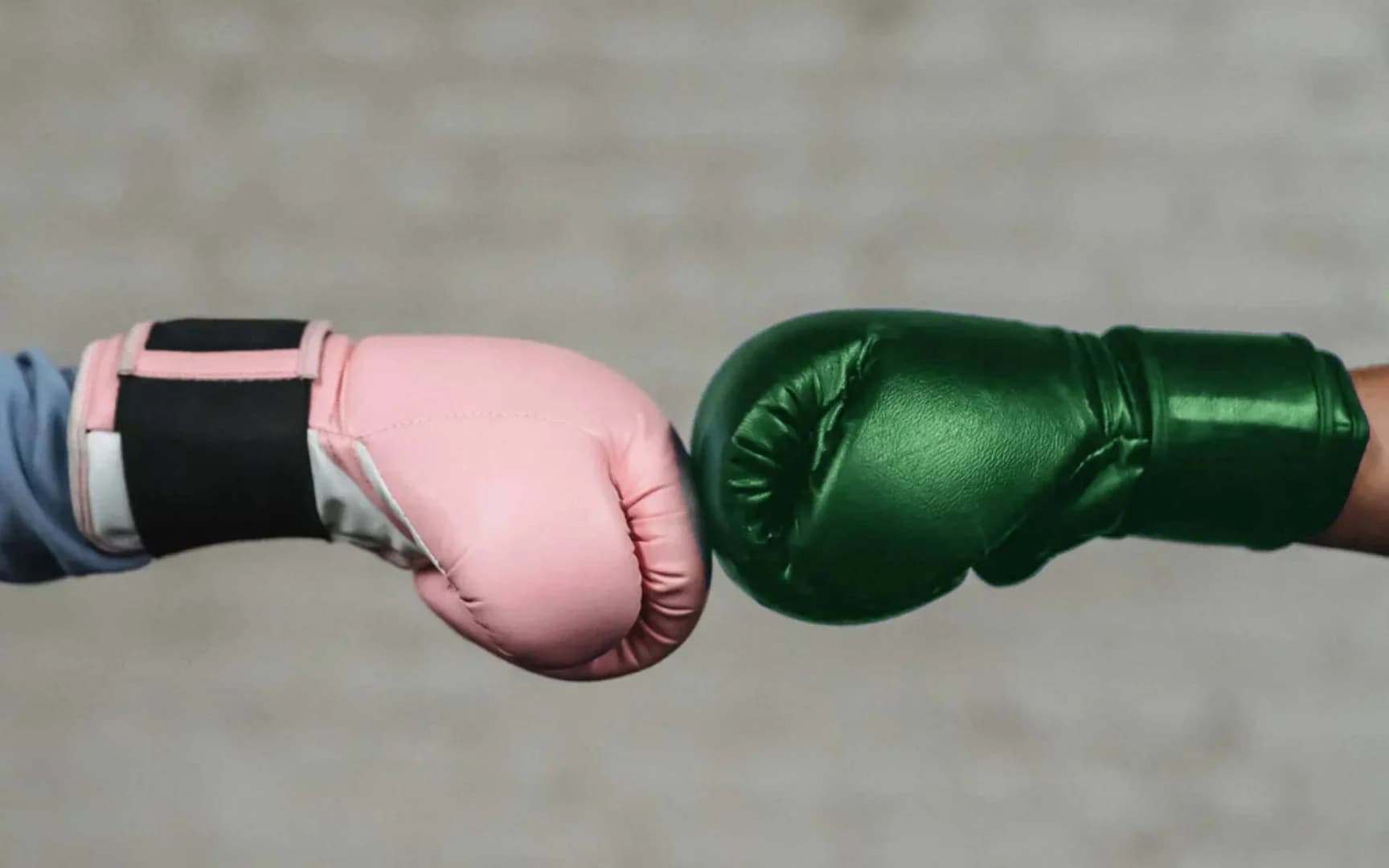En rosa boxningshandske slår mot en grön boxningshandske