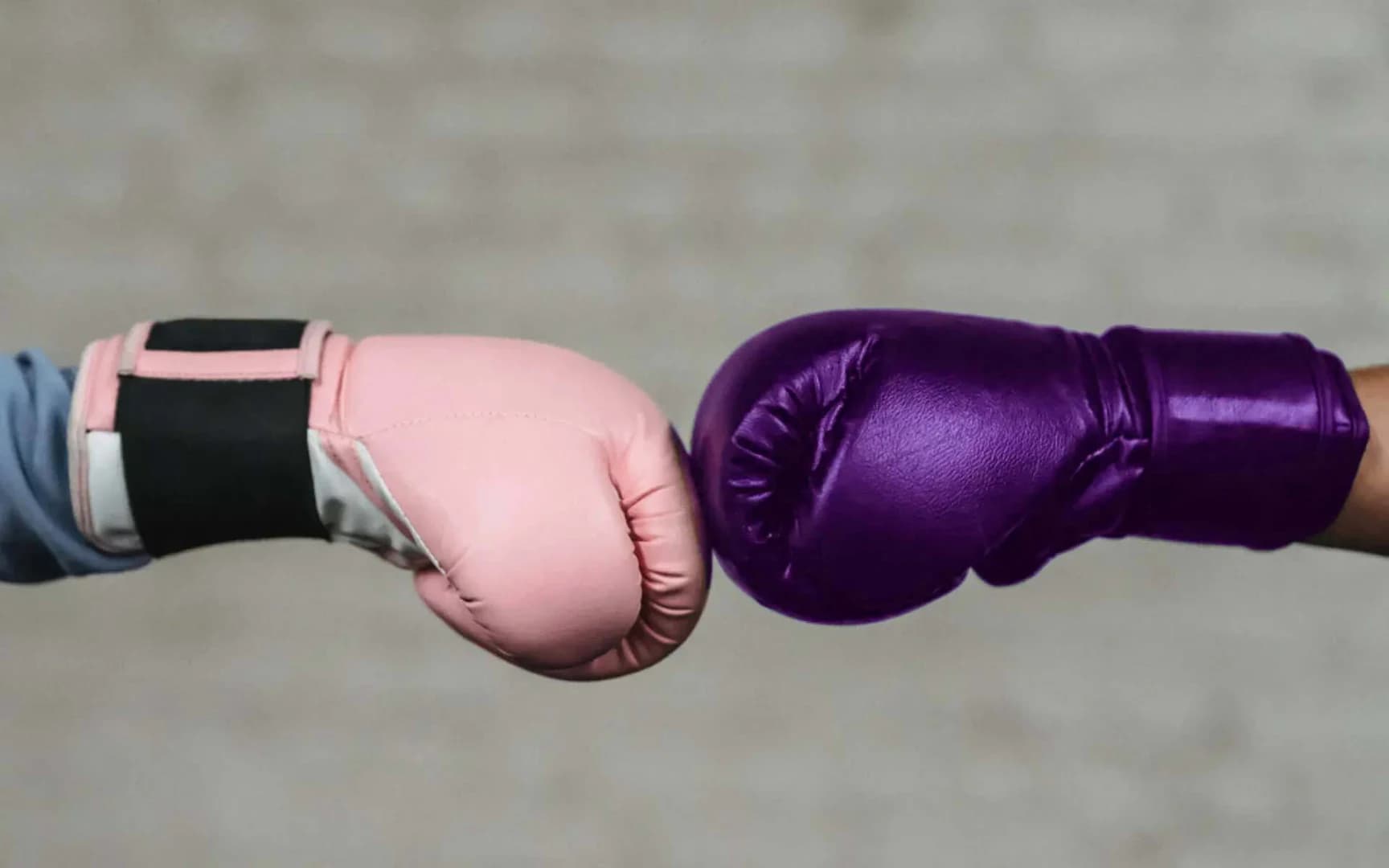 En rosa boxningshandske slår mot en lila boxningshandske