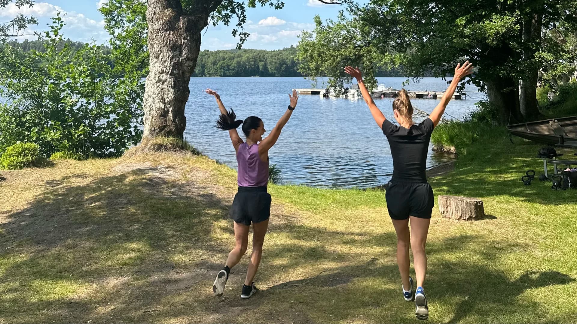 Två kvinnor springer på en gräsmatta med armarna upp i luften.