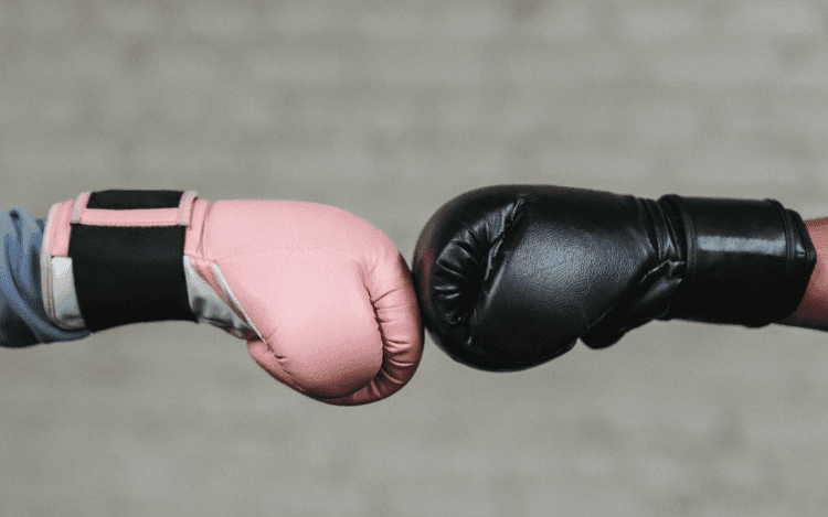 Rosa boxningshandske slår mot svart boxningshandske