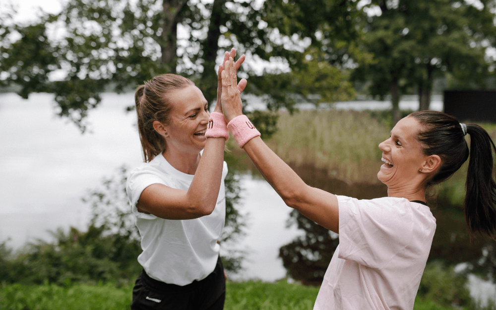 Två glada kvinnor som tränat gör high five med varandra