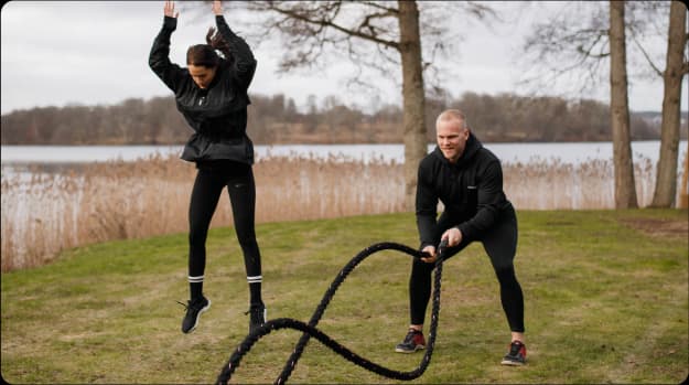 En man och kvinna tränar med kroppsvikt och battle ropes