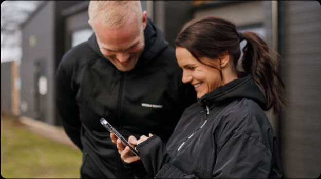 En man och en kvinna tittar i telefonen på weekly revolts app